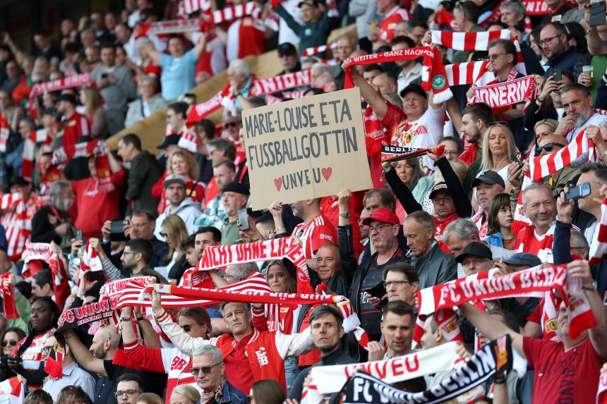 A Union Berlin fan holds up a sign that calls Eta a “<em>Fußballgöttin!</em>” (“<a href=