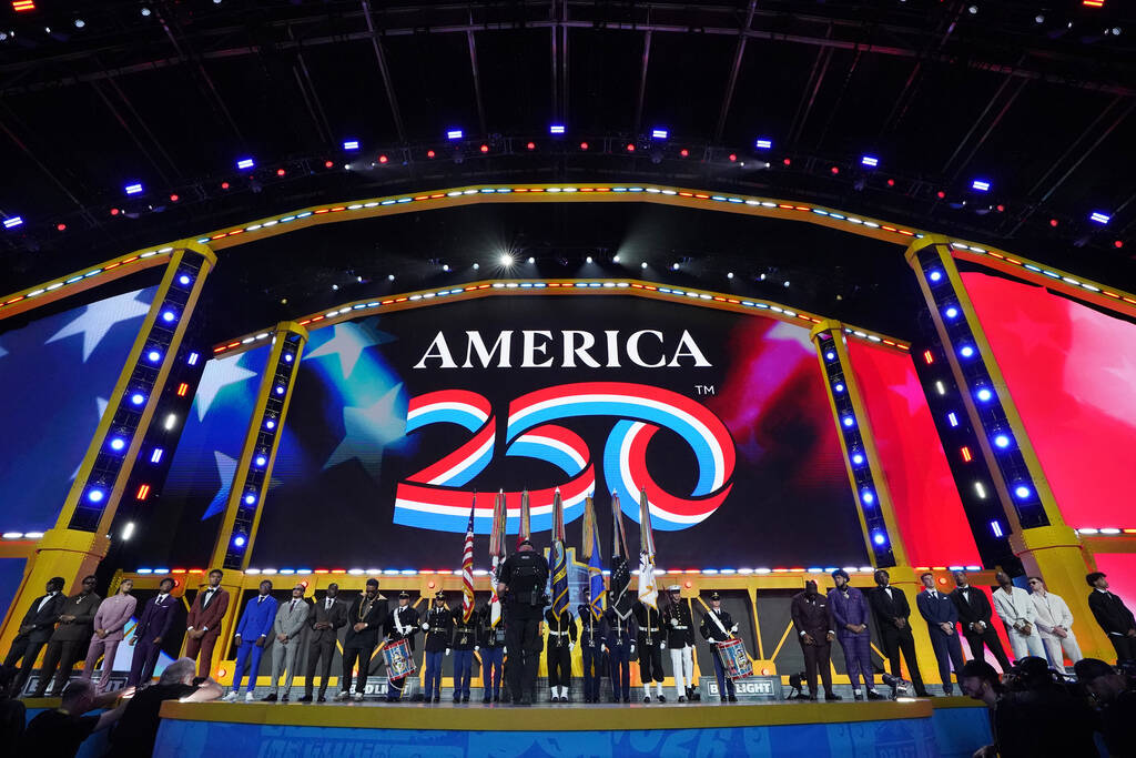 College players stand on the stage as flags are presented during the first round of the NFL foo ...