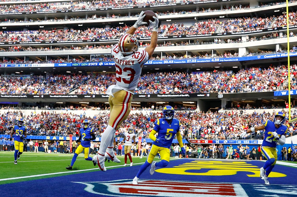 Christian McCaffrey #23 of the San Francisco 49ers catches the ball for a touchdown as Jalen Ramsey #5 and Taylor Rapp #24 of the Los Angeles Rams defend.