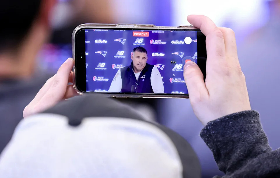 New England Patriots head coach Mike Vrabel, displayed on a mobile phone, speaks during an NFL football press conference, Tuesday, April 21, 2026, in Foxborough, Mass. (AP Photo/Mark Stockwell)