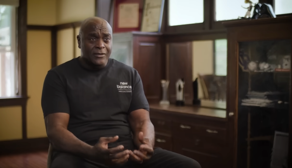 Person discussing in a formal setting with trophies displayed.