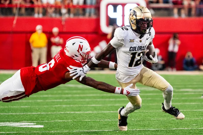 Sep 7, 2024; Lincoln, Nebraska, USA; Colorado Buffaloes wide receiver Travis Hunter (12) stiff arms Nebraska Cornhuskers defensive back Tommi Hill (6) during the second quarter at Memorial Stadium. Mandatory Credit: Dylan Widger-Imagn Images