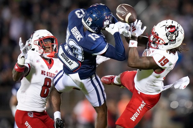 North Carolina State safety Bishop Fitzgerald (19) and defensive back Robert Kennedy (8) break up a pass to UConn wide receiver James Burns (13) during the first half an NCAA college football game in East Hartford, Conn., Thursday, Aug. 31, 2023. (AP Photo/Bryan Woolston)