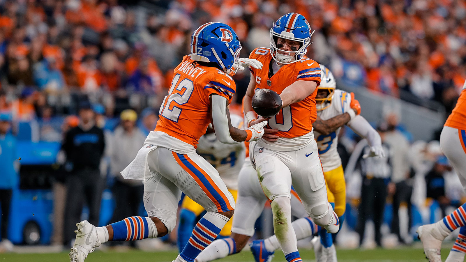 Denver Broncos quarterback Bo Nix (10) hands the ball off to running back RJ Harvey (12) in the third quarter against the Los Angeles Chargers at Empower Field at Mile High.