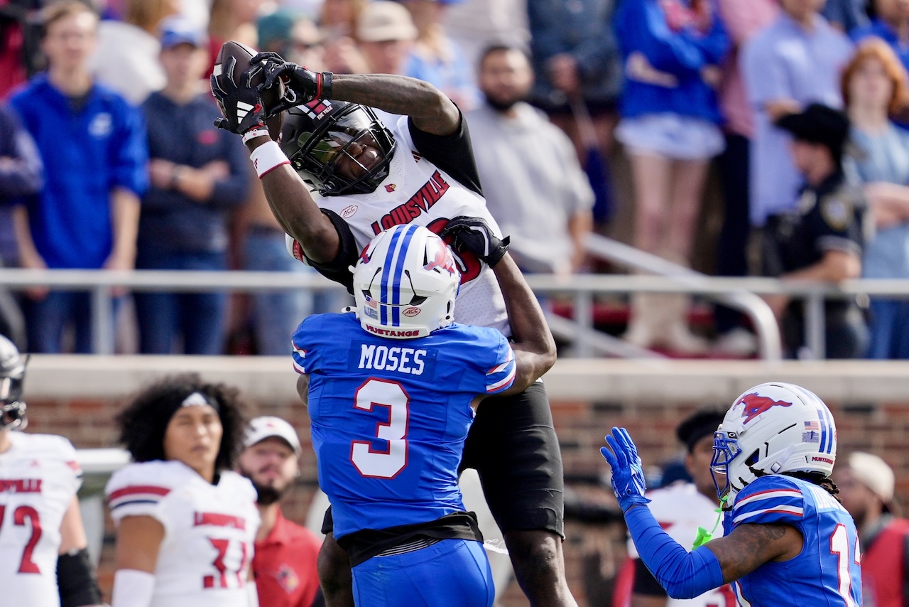 Louisville wide receiver Chris Bell (0) catches a pass as SMU safety Ahmaad Moses (3) defends in the first half of an NCAA college football game Saturday, Nov. 22, 2025, in Dallas. (AP Photo/Tony Gutierrez)