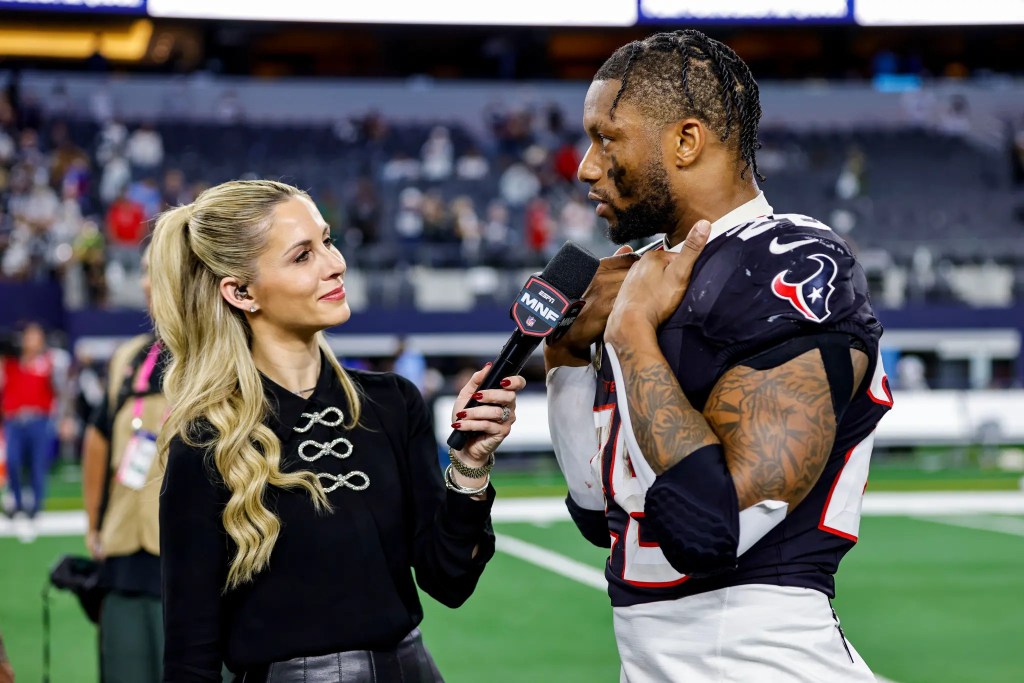 A blonde reporter with a microphone interviewing a football player on the field.