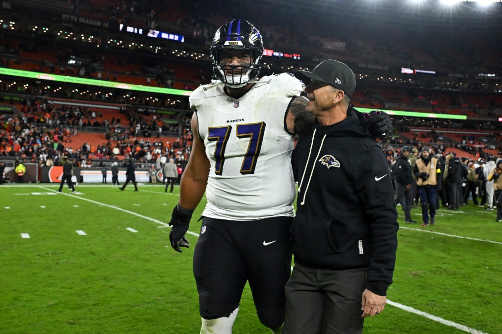 Offensive lineman Daniel Faalele (77) with Johjn Harbaugh after a Ravens win over the Browns on Nov. 16, 2025.