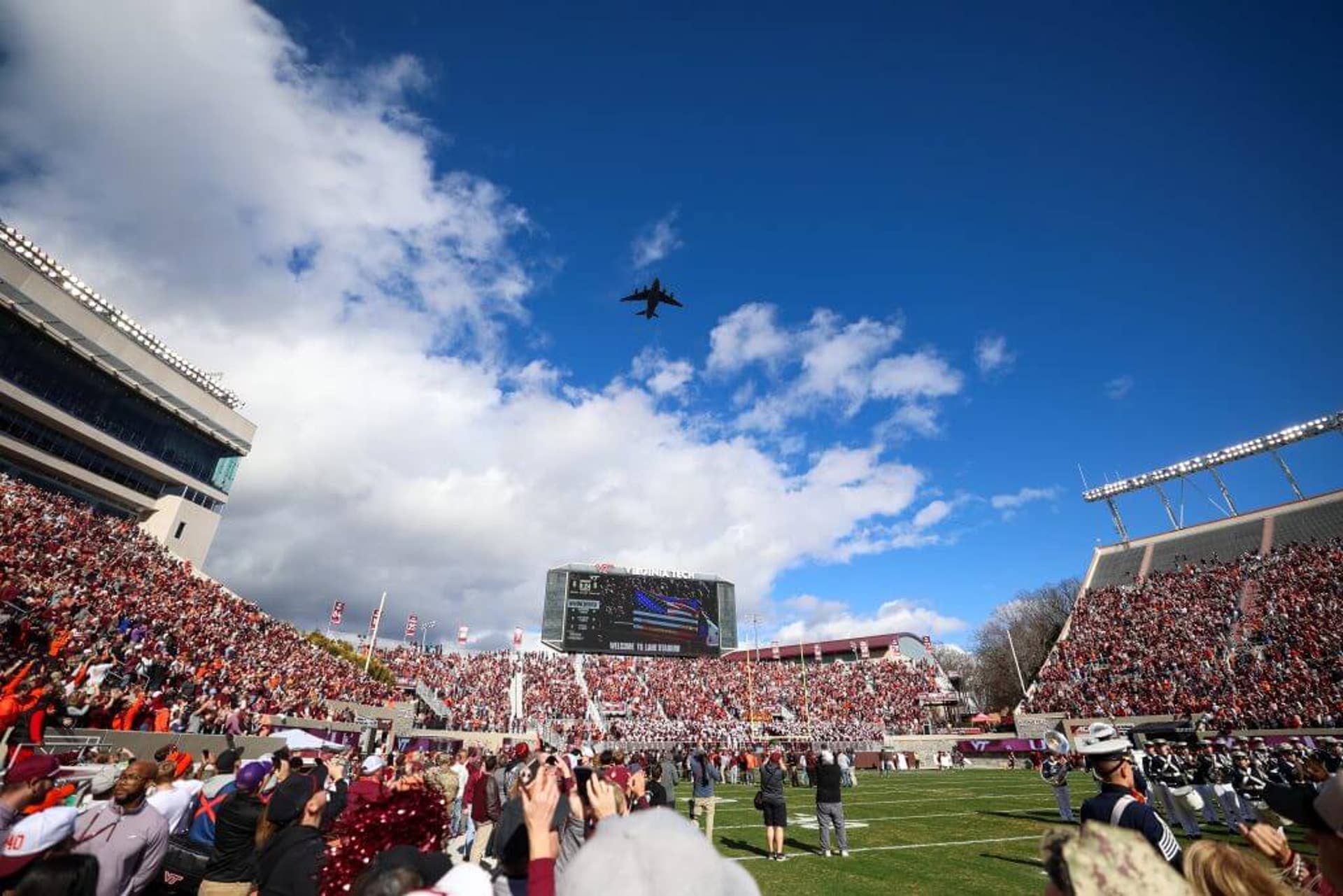 A U.S. Air Force C-17 cargo plane passes over Lane Stadium as fans look on.