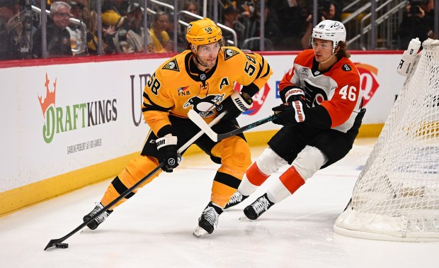 Penguins' Kris Letang skates with the puck against Flyers' Trevor Zegras in the second period of Game 1 of the first round of the 2026 Stanley Cup Playoffs at PPG PAINTS Arena on Saturday in Pittsburgh. (Photo by Justin Berl/Getty Images)
