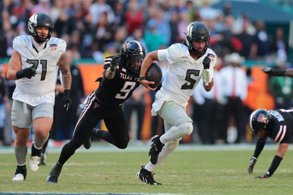 Jan 1, 2026; Miami Gardens, FL, USA; Oregon Ducks quarterback Dante Moore (5) carries the ball as Texas Tech Red Raiders linebacker Romello Height (9) defends during the second half of the 2025 Orange Bowl and quarterfinal game of the College Football Playoff at Hard Rock Stadium.