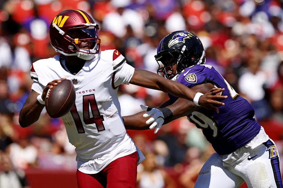 Aug 23, 2025; Landover, Maryland, USA; Washington Commanders quarterback Josh Johnson (14) runs away from Baltimore Ravens linebacker Jay Higgins IV (49) during the third quarter at Northwest Stadium. Mandatory Credit: Peter Casey-Imagn Images