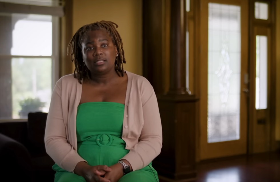 Individual in a green dress seated indoors.