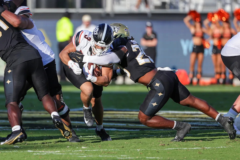 Nov 22, 2025; Orlando, Florida, USA; Oklahoma State Cowboys running back Sesi Vailahi (3) is tackled by UCF Knights linebacker Lewis Carter (20) during the first quarter at Acrisure Bounce House. Mandatory Credit: Mike Watters-Imagn Images