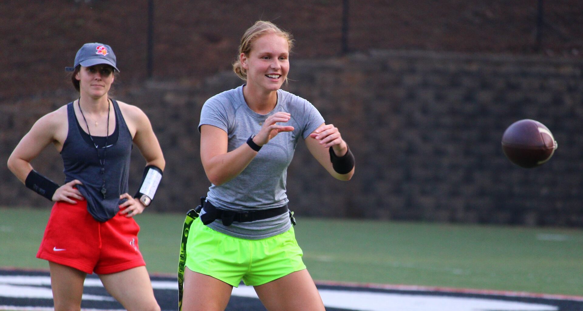 A flag football coach watches a quarterback prepare to catch the ball.