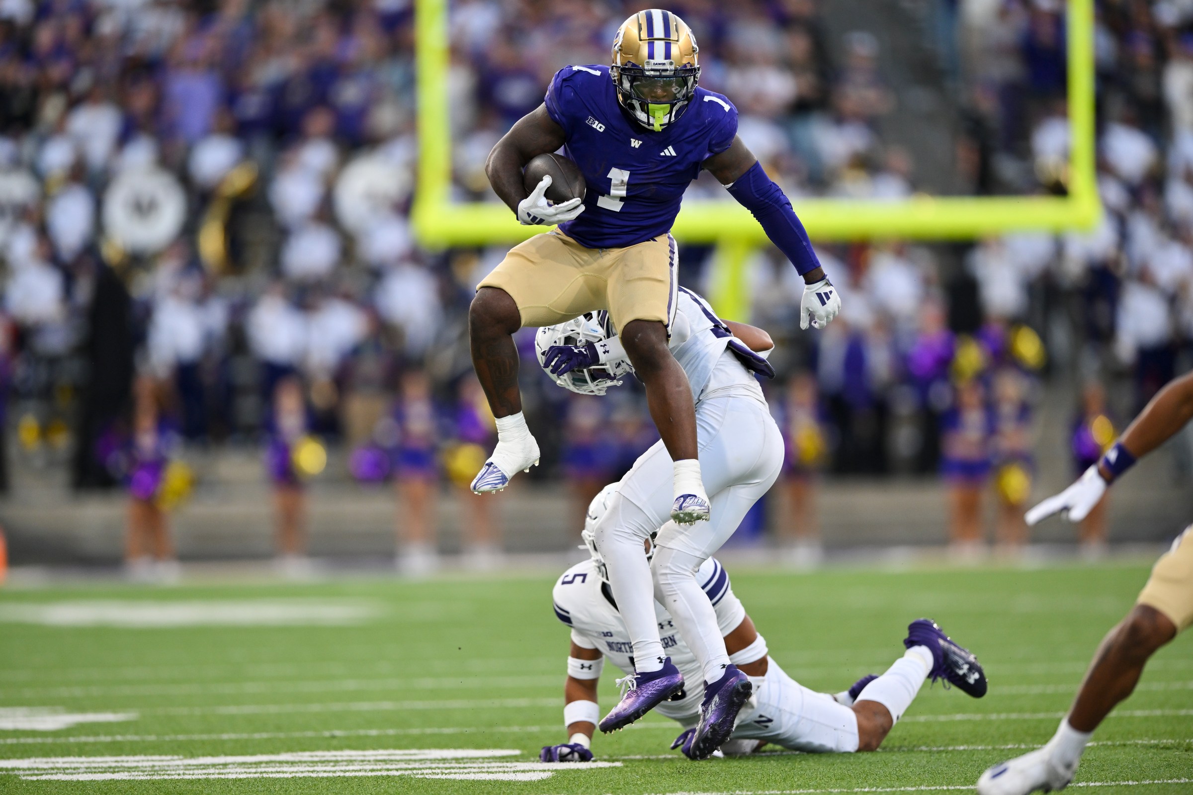 SEATTLE, WASHINGTON - SEPTEMBER 21: Jonah Coleman #1 of the Washington Huskies leaps over Evan Smith #12 of the Northwestern Wildcats during the third quarter of the game at Husky Stadium on September 21, 2024 in Seattle, Washington. The Huskies defeated the Wildcats 24-5. (Photo by Alika Jenner/Getty Images)