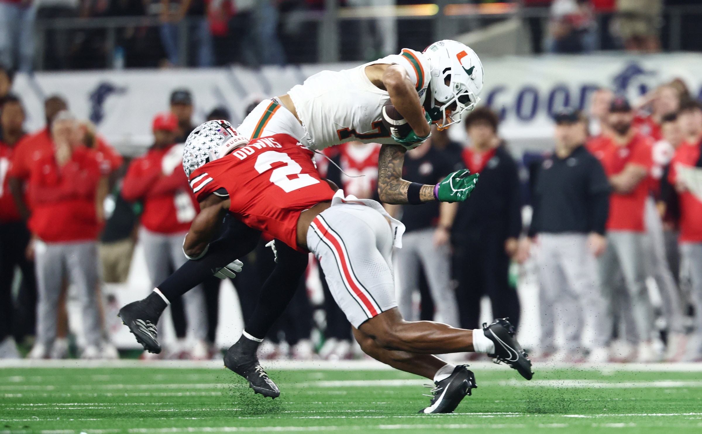 ARLINGTON, TEXAS - DECEMBER 31: CJ Daniels #7 of the Miami Hurricanes is tackled by Caleb Downs #2 of the Ohio State Buckeyes in the first half of the College Football Playoff Quarter Final Game at AT&T Stadium on December 31, 2025 in Arlington, Texas. (Photo by CFP/Getty Images)