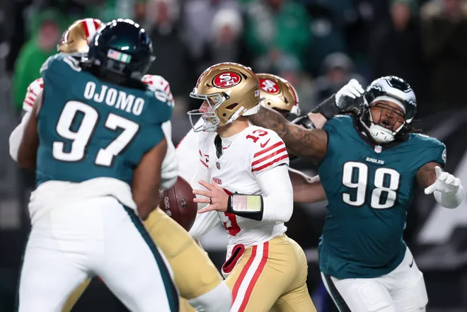 Jan 11, 2026; Philadelphia, PA, USA; San Francisco 49ers quarterback Brock Purdy (13) looks to pass the ball under pressure from Philadelphia Eagles defensive tackle Moro Ojomo (97) and defensive tackle Jalen Carter (98) during the third quarter in an NFC Wild Card Round game at Lincoln Financial Field. Mandatory Credit: Bill Streicher-Imagn Images