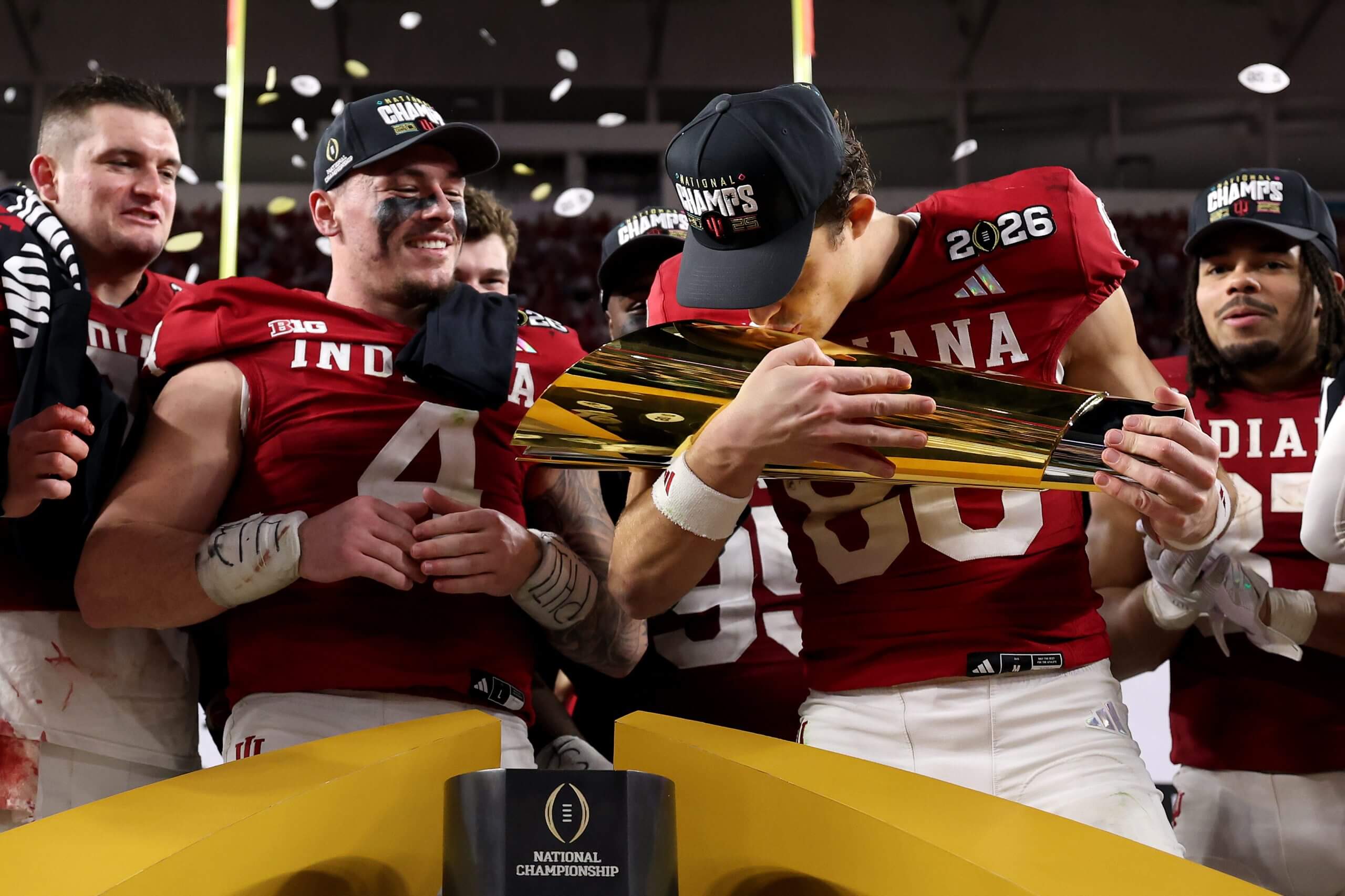 Indiana's Charlie Becker kisses the CFP championship trophy as teammates look on
