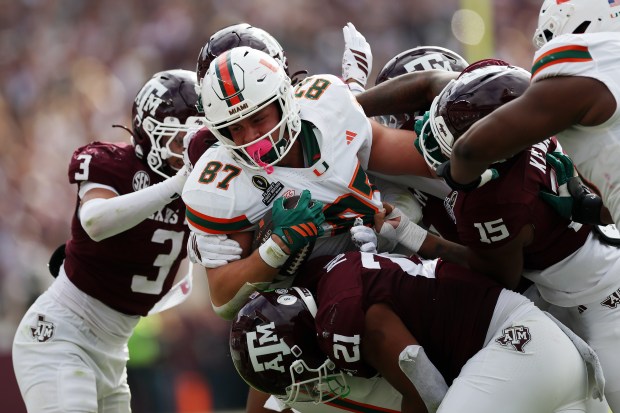 Alex Bauman #87 of the Miami Hurricanes runs with the ball while being tackled by Taurean York #21 and Rylan Kennedy #15 of the Texas A&M Aggies in the second quarter during the 2025 College Football Playoff First Round Game at Kyle Field on Dec. 20, 2025 in College Station, Texas. (Photo by Tim Warner/Getty Images)