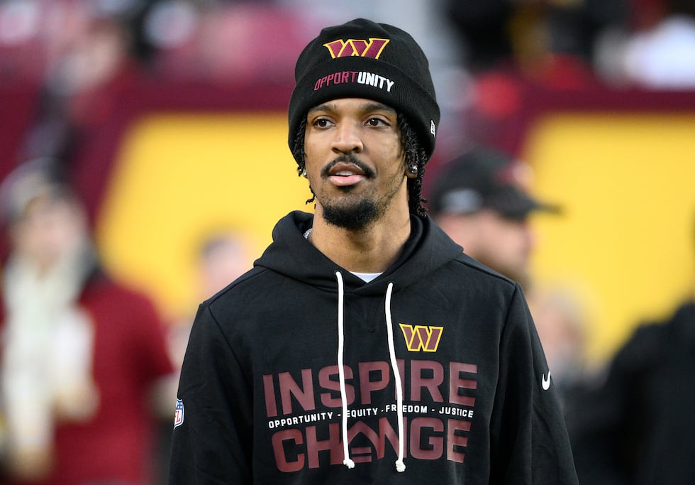 Injured Washington Commanders quarterback Jayden Daniels looks on before an NFL football game...