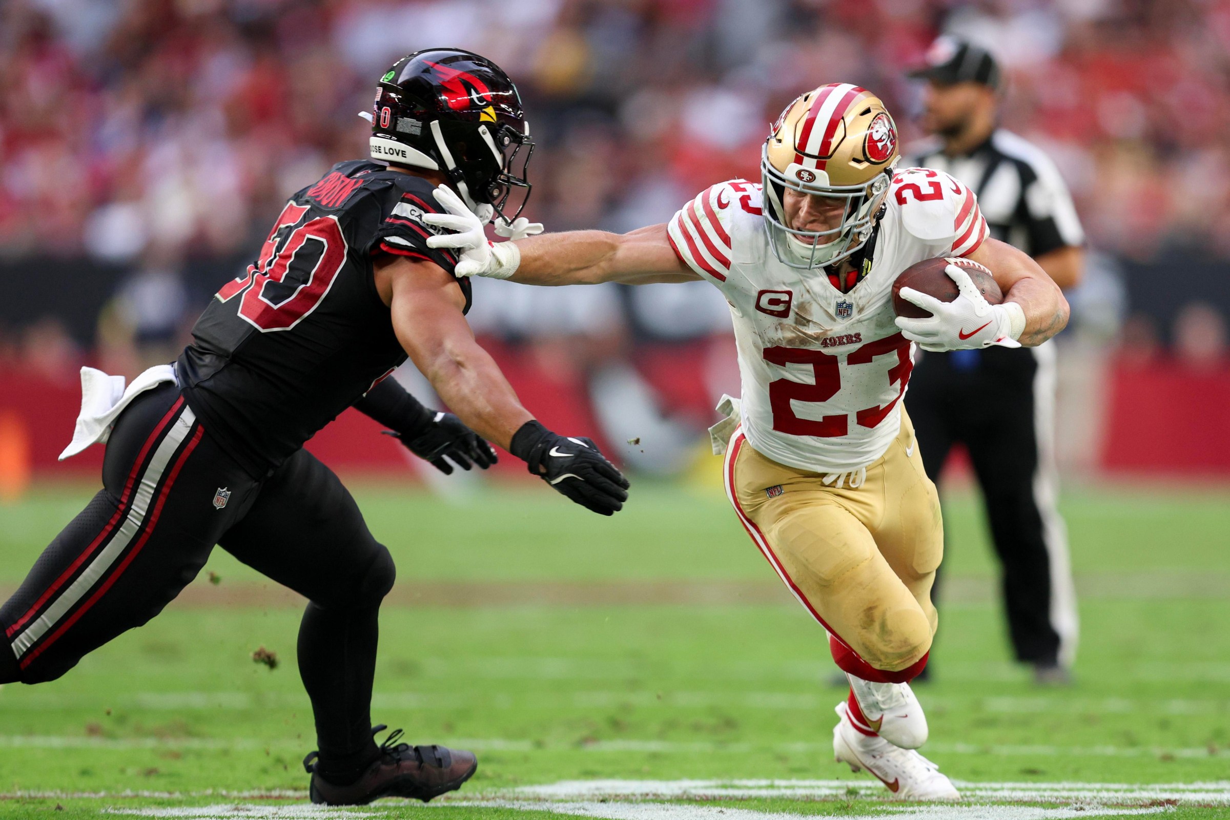 Cody Simon #50 of the Arizona Cardinals attempts to tackle Christian McCaffrey #23 of the San Francisco 49ers