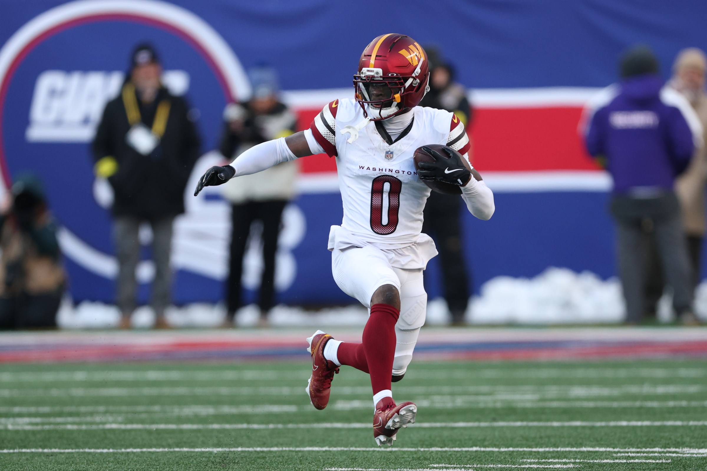 Dec 14, 2025; East Rutherford, New Jersey, USA; Washington Commanders cornerback Mike Sainristil (0) runs the ball after an interception during the second quarter against the New York Giants at MetLife Stadium. Mandatory Credit: Vincent Carchietta-Imagn Images