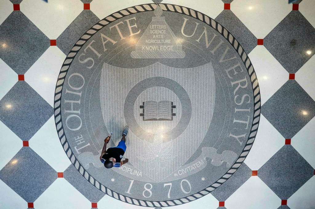 A person walks over the Ohio State University's emblem on the floor of the campus student union.