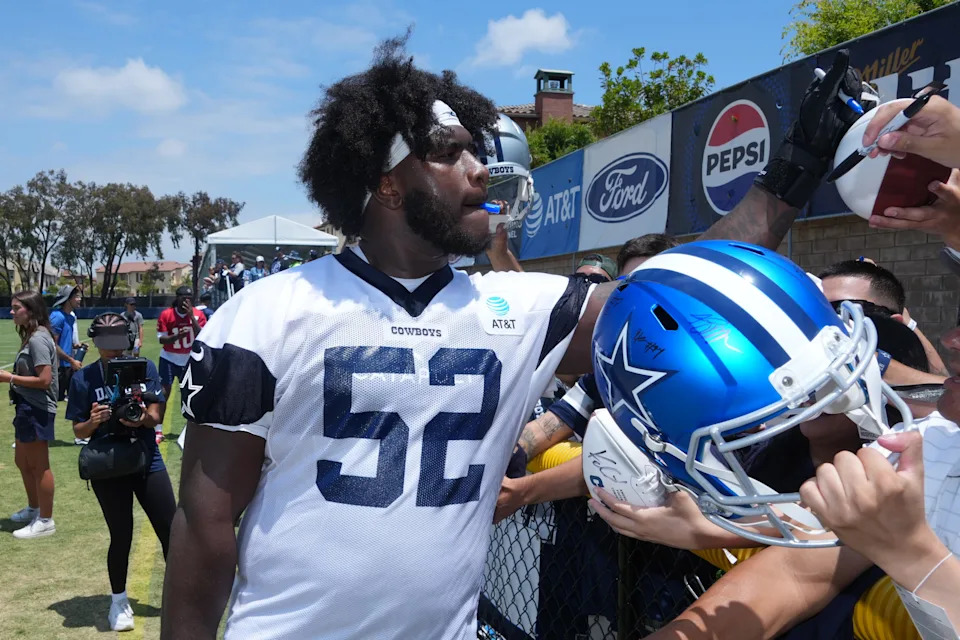 Jul 22, 2025; Oxnard, CA, USA; Dallas Cowboys guard Tyler Booker (52) signs autographs during training camp at the River Ridge Fields. Mandatory Credit: Kirby Lee-Imagn Images