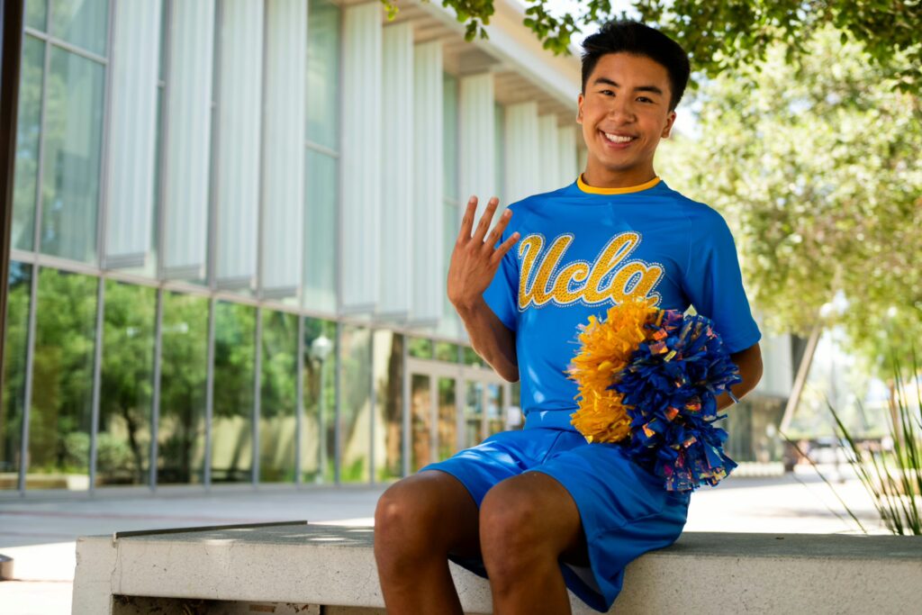 UCLA Dance Team member Ryan Bucu sits and holds up four fingers. The second male member of the team has amassed more than 22,000 followers on Instagram and 18,000 followers on TikTok.