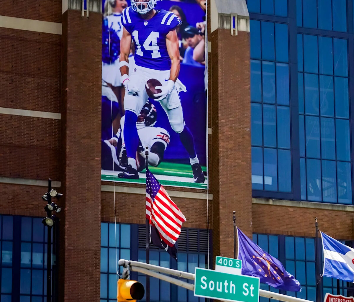 Colts players with banners (and a statue) at Lucas Oil Stadium