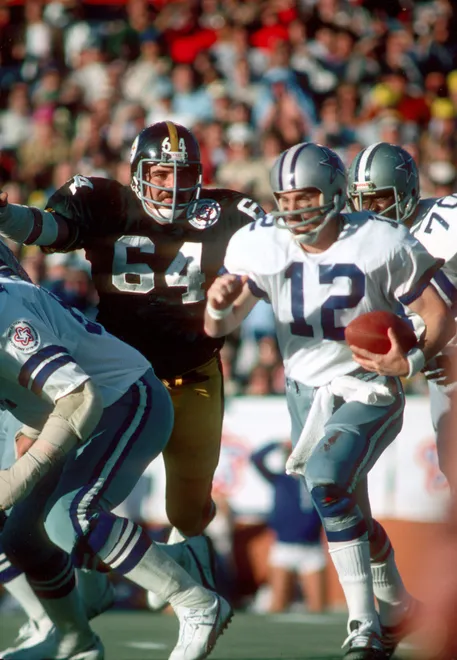 Jan 18, 1976; Miami, FL, USA; Pittsburgh Steelers defensive lineman Steve Furness (64) pressures Dallas Cowboys quarterback Roger Staubach (12) during Super Bowl X at the Orange Bowl.  Pittsburgh defeated the Cowboys 21-17 to win their second Super Bowl victory. Mandatory Credit: Tony Tomsic-USA TODAY Sports