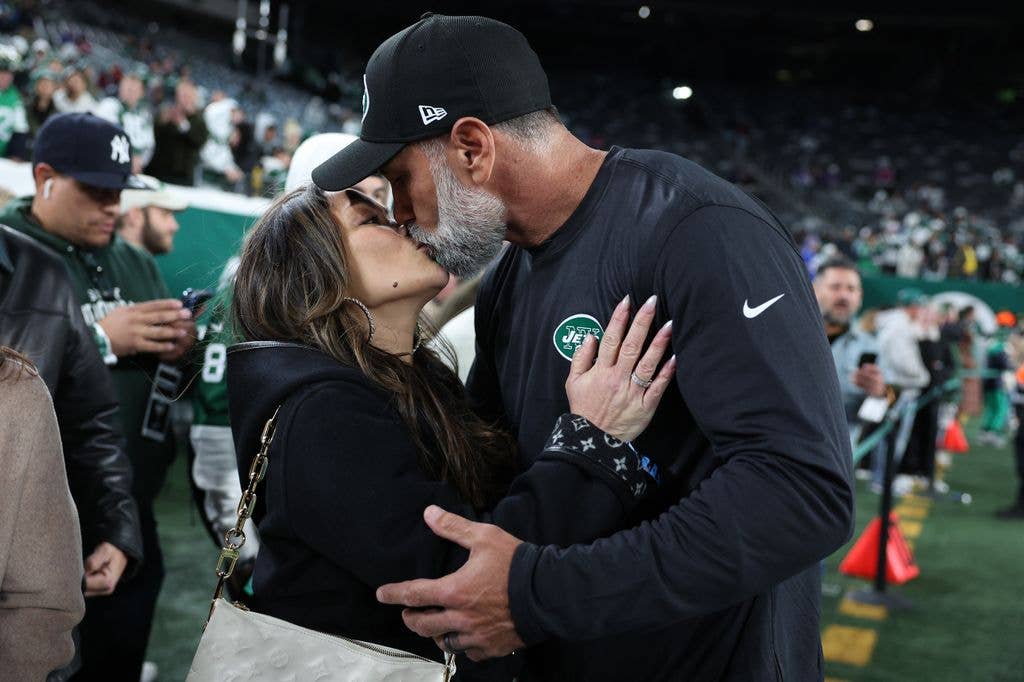 Jeff and Cristina Ulbrich sharing a kiss on the lips at a sports event.