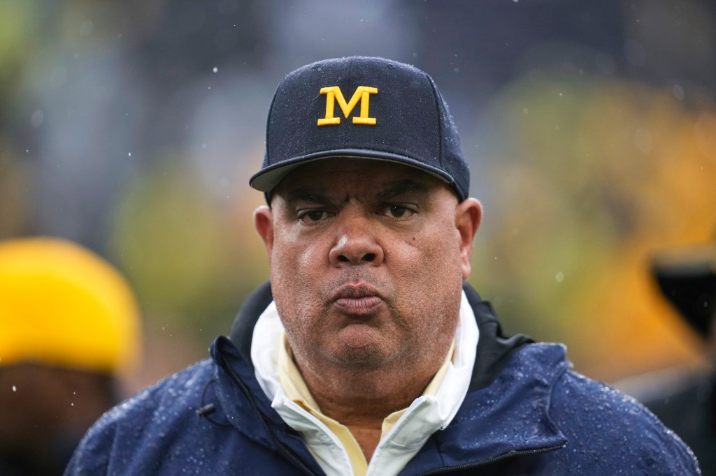 Michigan athletic director Warde Manuel in a navy cap with a yellow M.