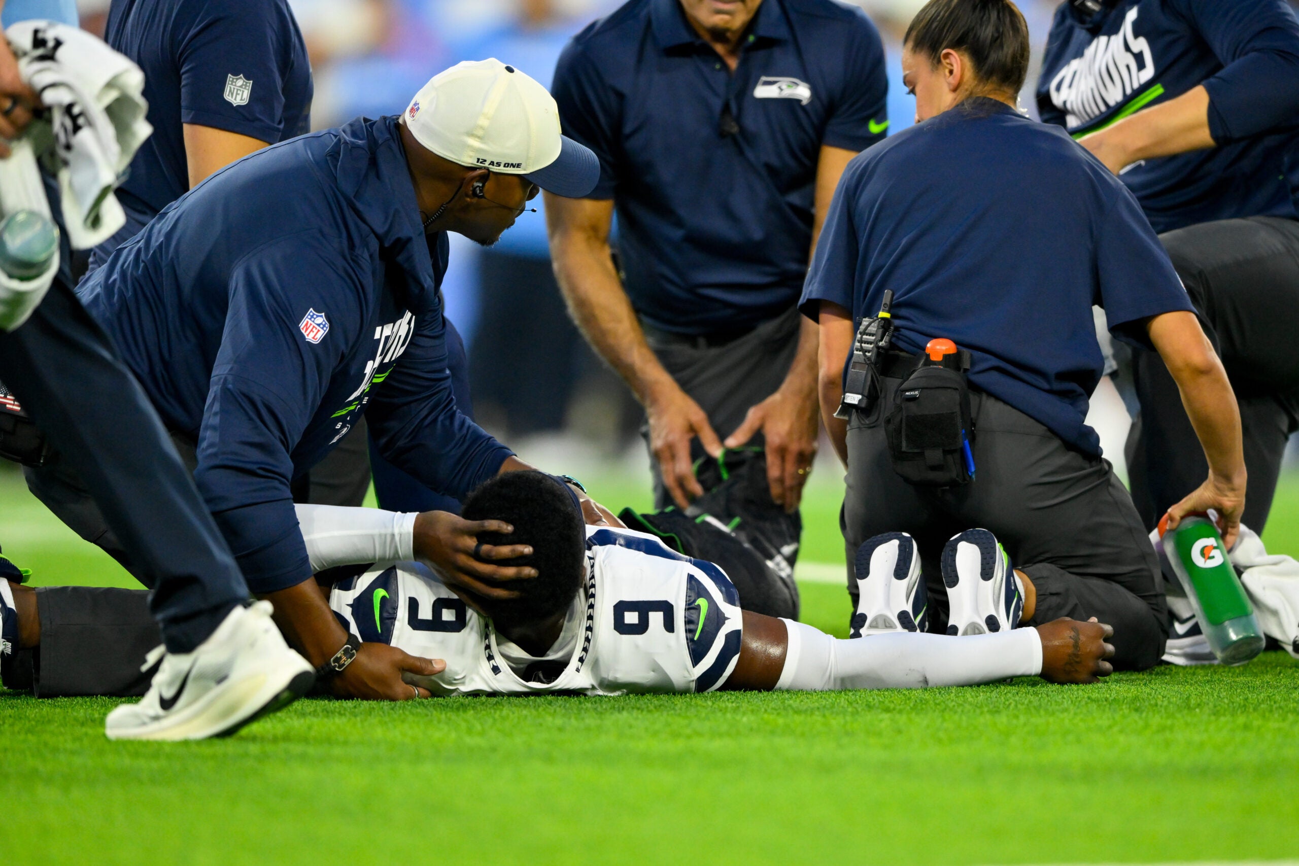 Aug 23, 2026; Nashville, Tennessee, USA; Seattle Seahawks trainer holds the ankle of safety Bud Clark (9) as they wait for the cart against the Tennessee Titans during the first half at Nissan Stadium.