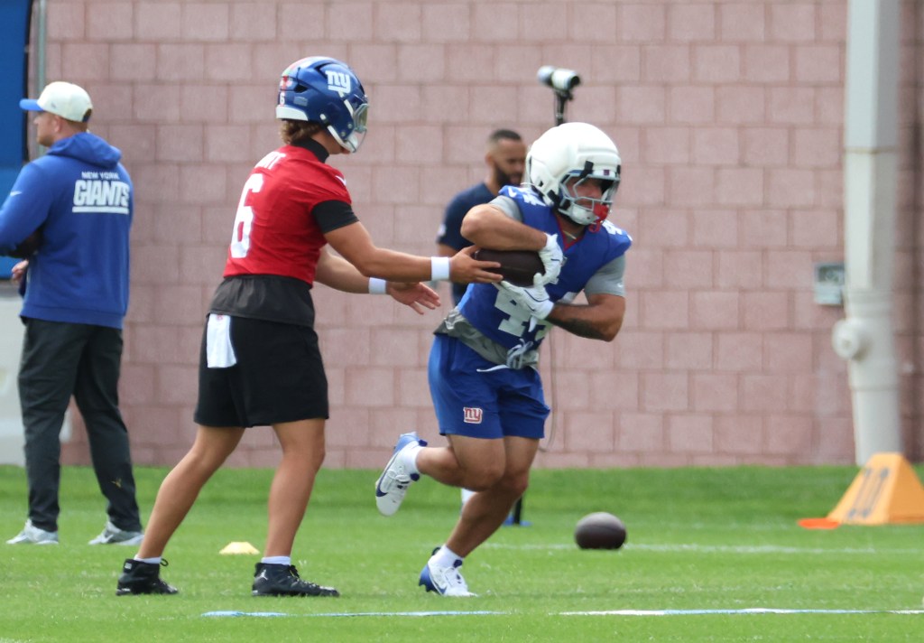 New York Giants quarterback Jaxson Dart hands the ball off to running back Cam Skattebo during practice.