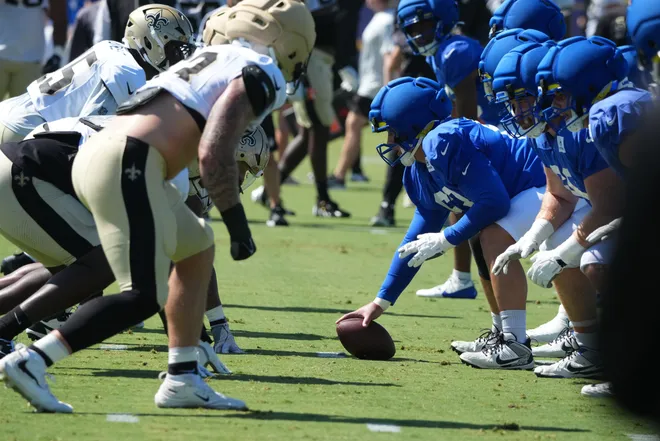 Aug 20, 2026; Woodland Hills, CA, USA; Helmets at the line of scrimmage as Los Angeles Rams center Dylan McMahon (63) snaps the ball wearing a Guardian helmet cap against the New Orleans Saints during a joint practice at Rams Practice Facility. Mandatory Credit: Kirby Lee-Imagn Images