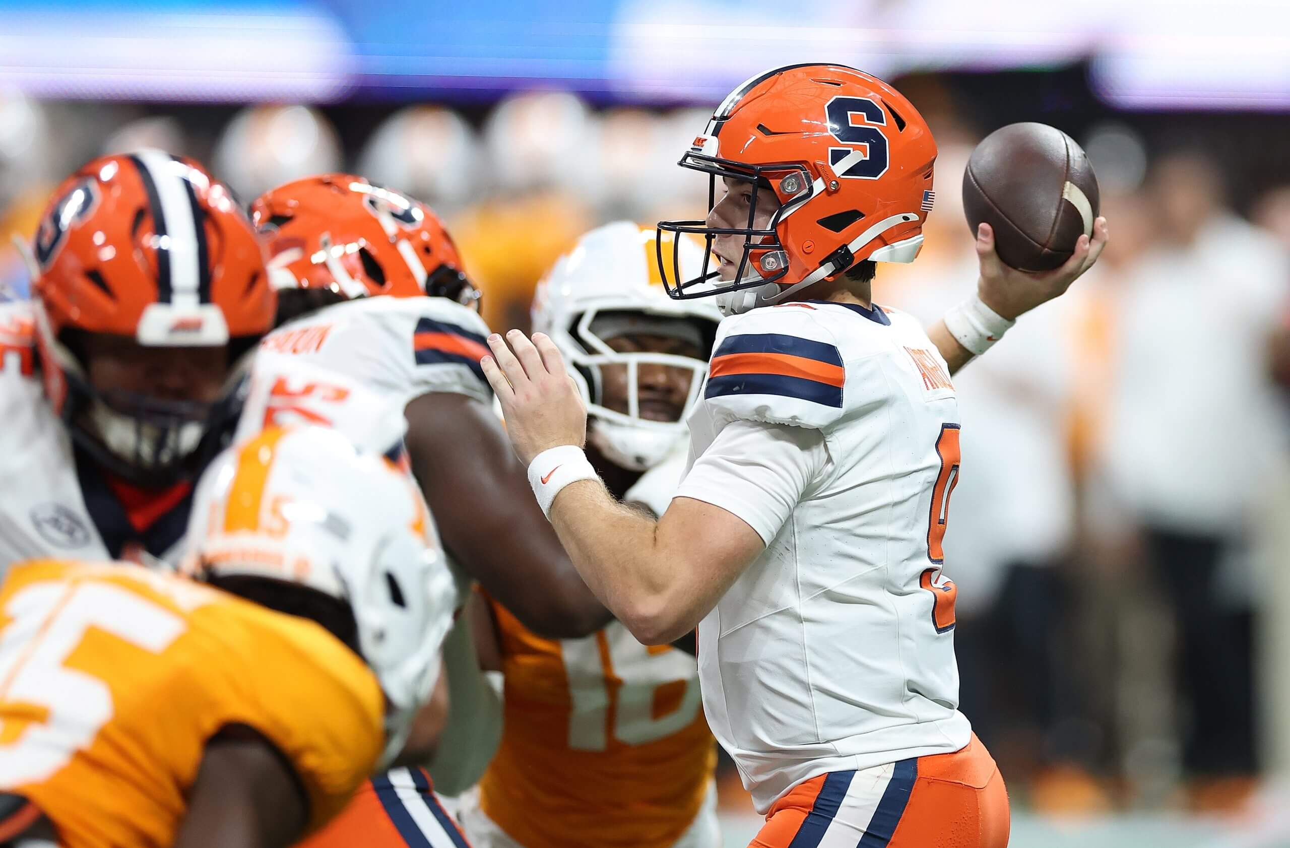 Steve Angeli raises his right arm and gets set to throw a pass as Syracuse players block Tennessee defenders