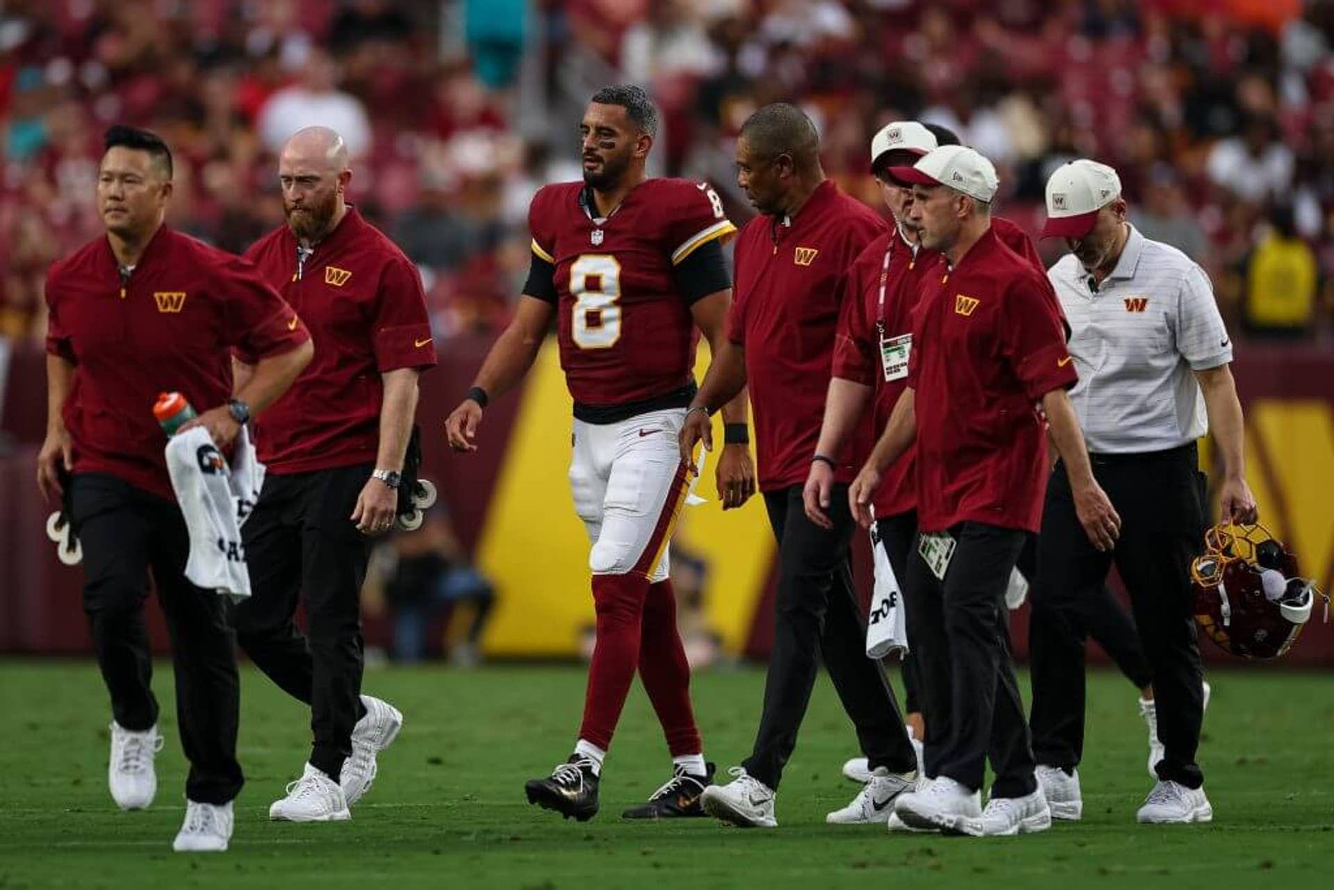 Marcus Mariota walks off the field with trainers after being injured in Washington's preseason game against the Miami Dolphins.