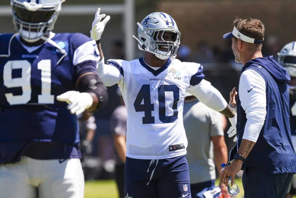 Dallas Cowboys linebacker Von Miller talks with head coach Brian Schottenheimer as he stretches during a joint training camp practice.