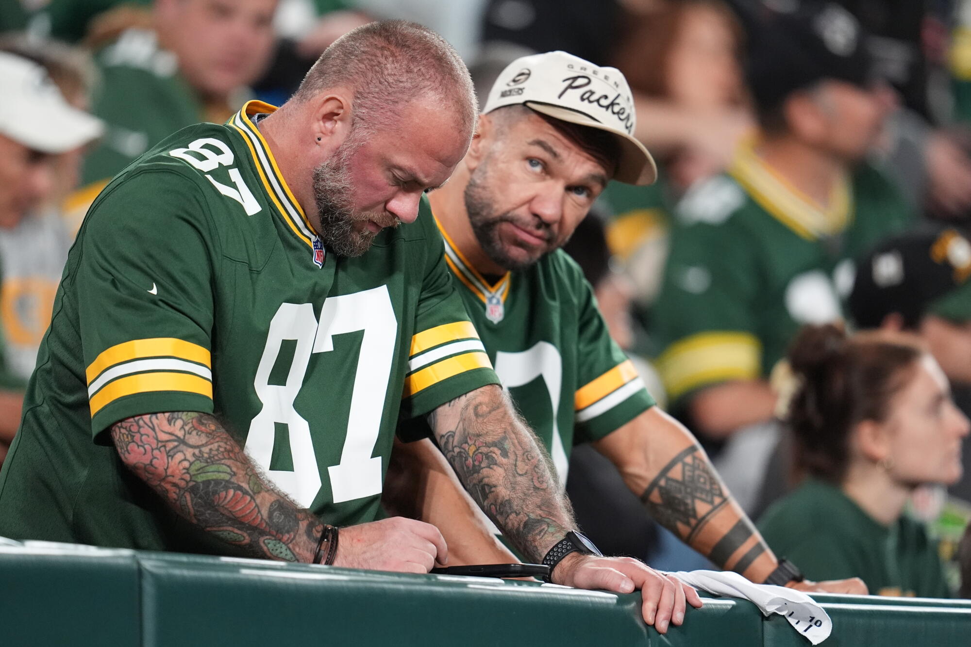 Green Bay Packers fans look unhappy standing at a railing in the stands at Lambeau Field