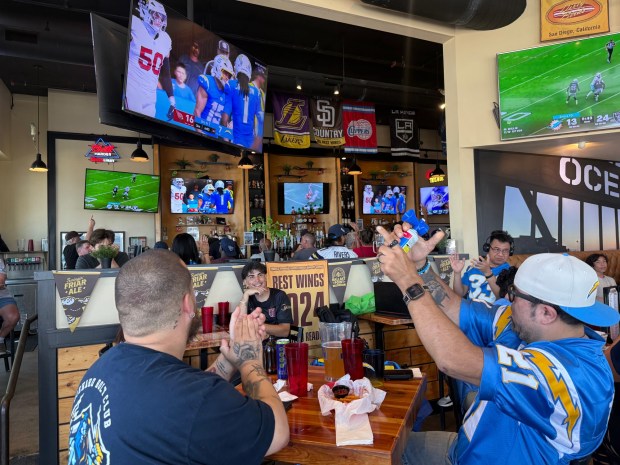 Chargers fan Mario Lopez (right, in jersey) blows an air horn following a Los Angeles touchdown during last Sunday's watch party at Dirty Birds in Ocean Beach. Lopez is a member of the San Diego chapter of the Die Hard Bolt Club. The group gathers to cheer on a team that moved to L.A. nearly a decade ago. "We're still here," Lopez said. (Eddie Brown, The San Diego Union-Tribune)