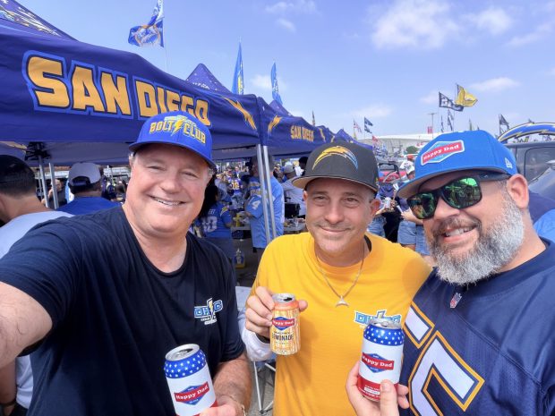 Matthrew Guccione, center, smiles as he tailgates before last week's Chargers-Cardinals game at SoFi Stadium. Guccione is president of the Die Hard Bolt Club; he was joined at the tailgate by Jonathan French, left, president of the Orange County chapter; and fellow Chargers fan Joe Bootow, who wore a Junior Seau jersey to L.A. (Matthew Guccione)