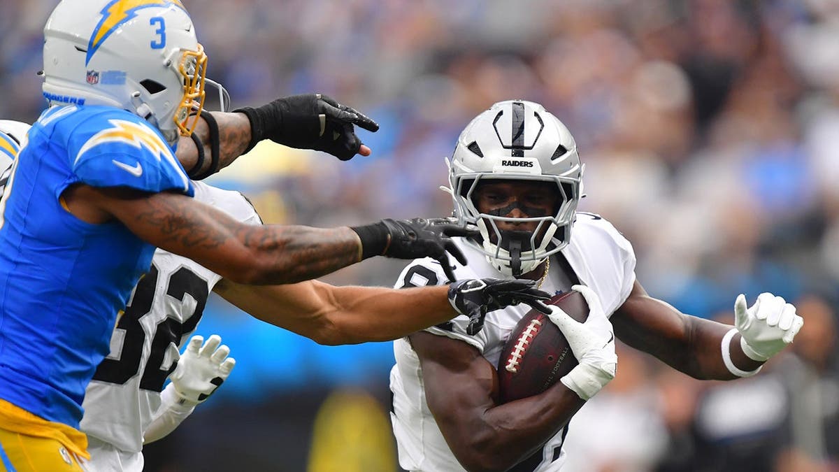 Dareke Young runs after a catch while Derwin James Jr. defends during an NFL game at SoFi Stadium.