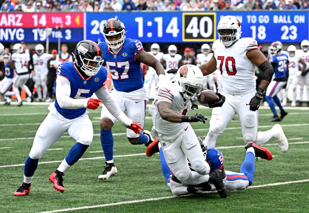 Arizona Cardinals running back Jeremiyah Love is tackled by New York Giants linebacker Arvell Reese during a game.