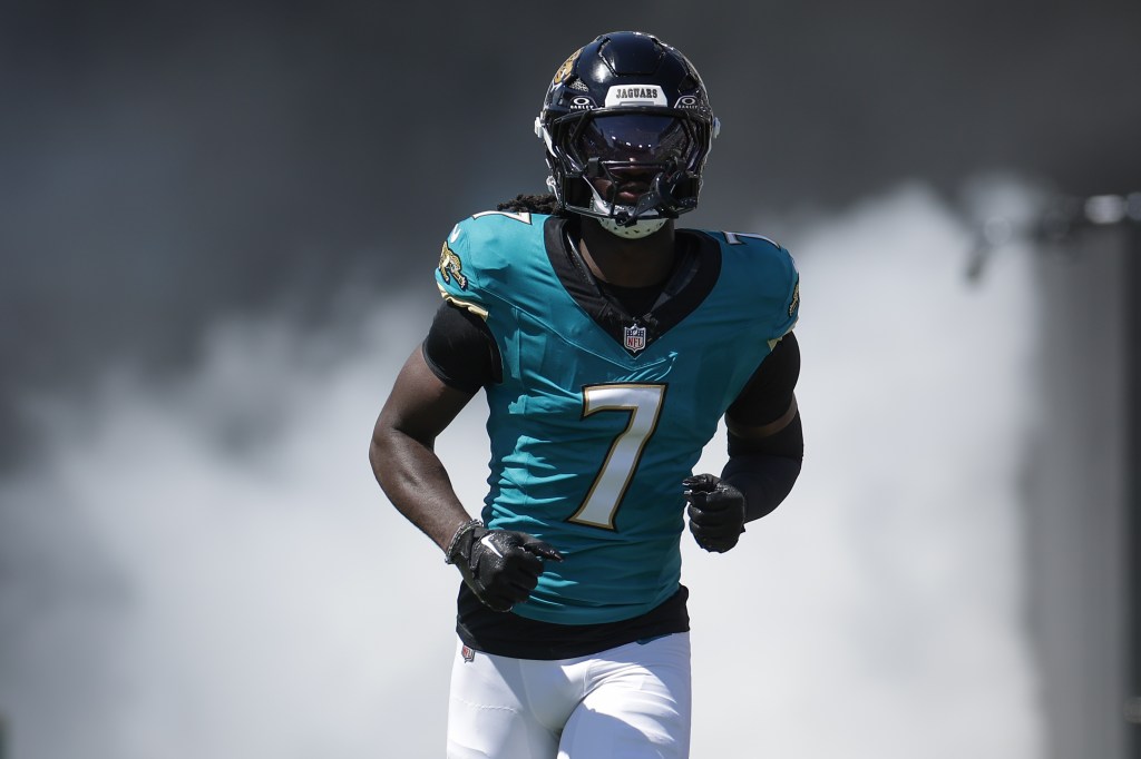 Jacksonville Jaguars player running on the field in a teal uniform.