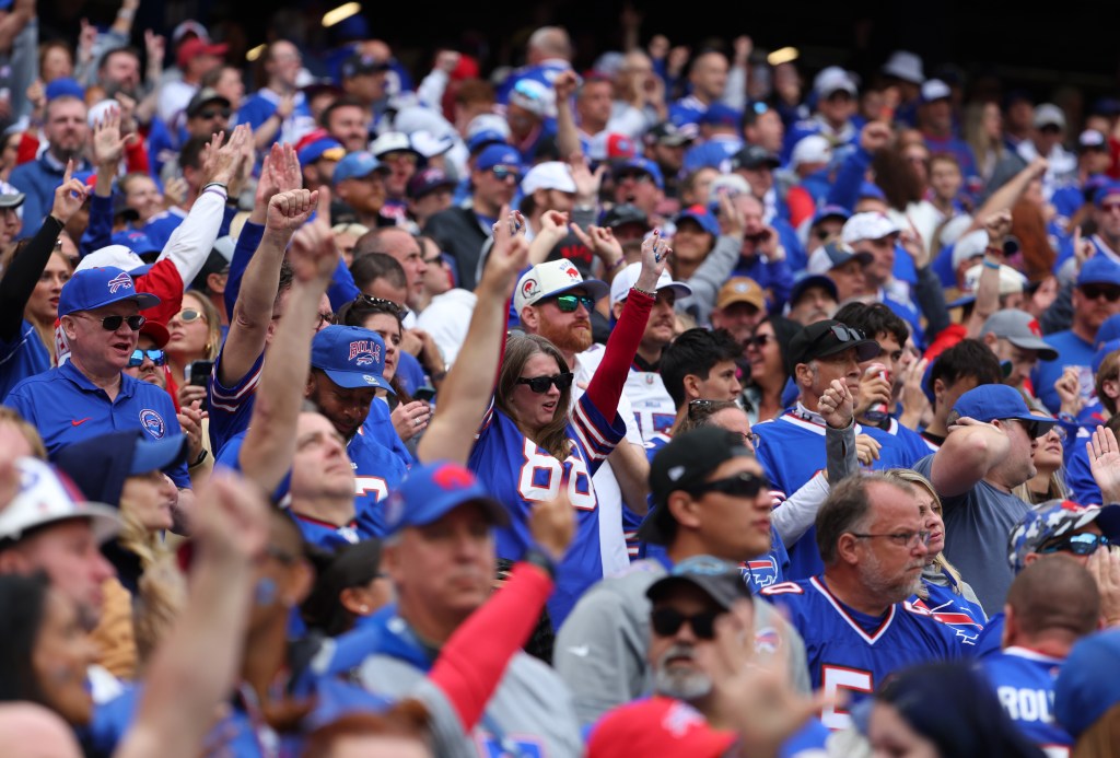 A large crowd of Buffalo Bills fans cheering in the stands, many wearing team jerseys and hats.
