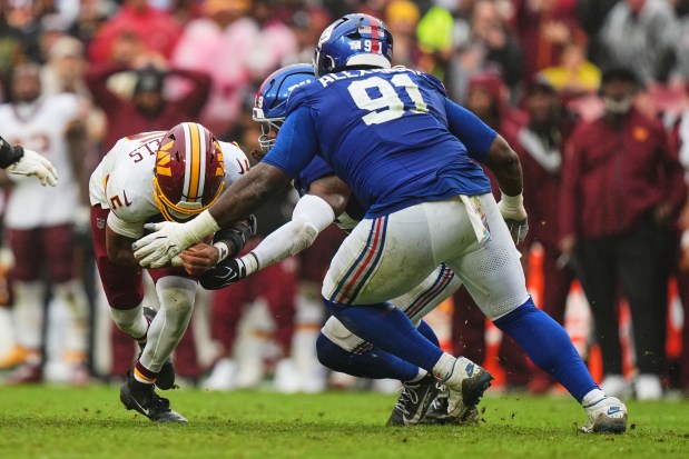 New York Giants' Darius Alexander (91) tackles Washington Commanders' Jayden Daniels (5) during the overtime of an NFL football game in Landover, Md., Sunday, Oct. 11, 2026. (AP Photo/Stephanie Scarbrough)