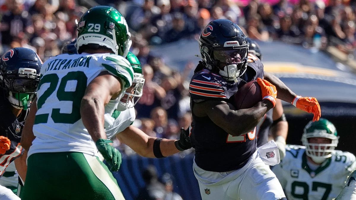 Kyle Monangai runs with the ball as Minkah Fitzpatrick defends during an NFL game.