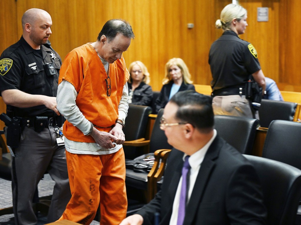 Zvi Levran in orange prison uniform being escorted out of courtroom after his sentencing