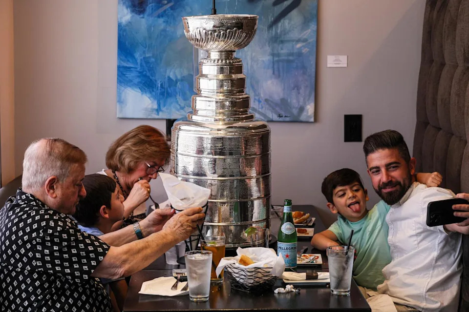 Nareg Dekermenjian uses his cell phone to take a picture of himself and his son, Oliver, and the Stanley Cup.